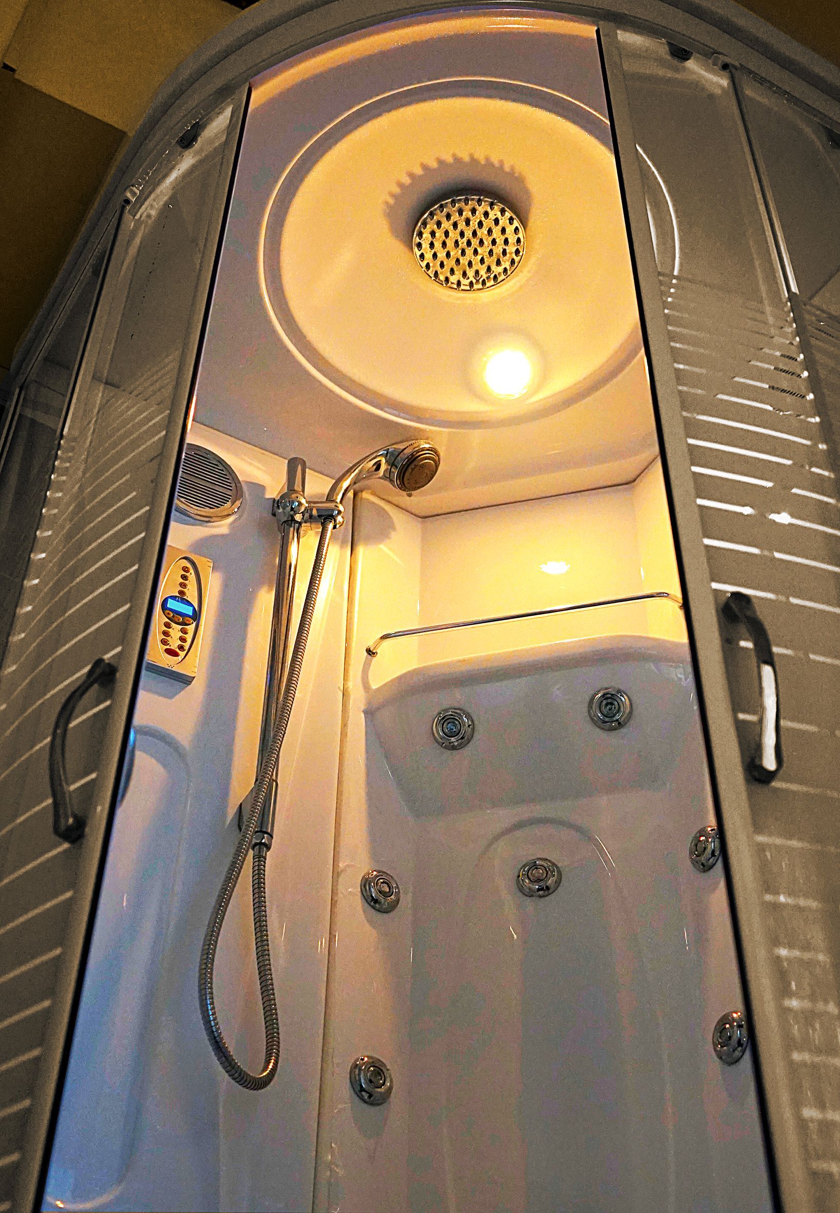 A shower stall with the door open and a shower head