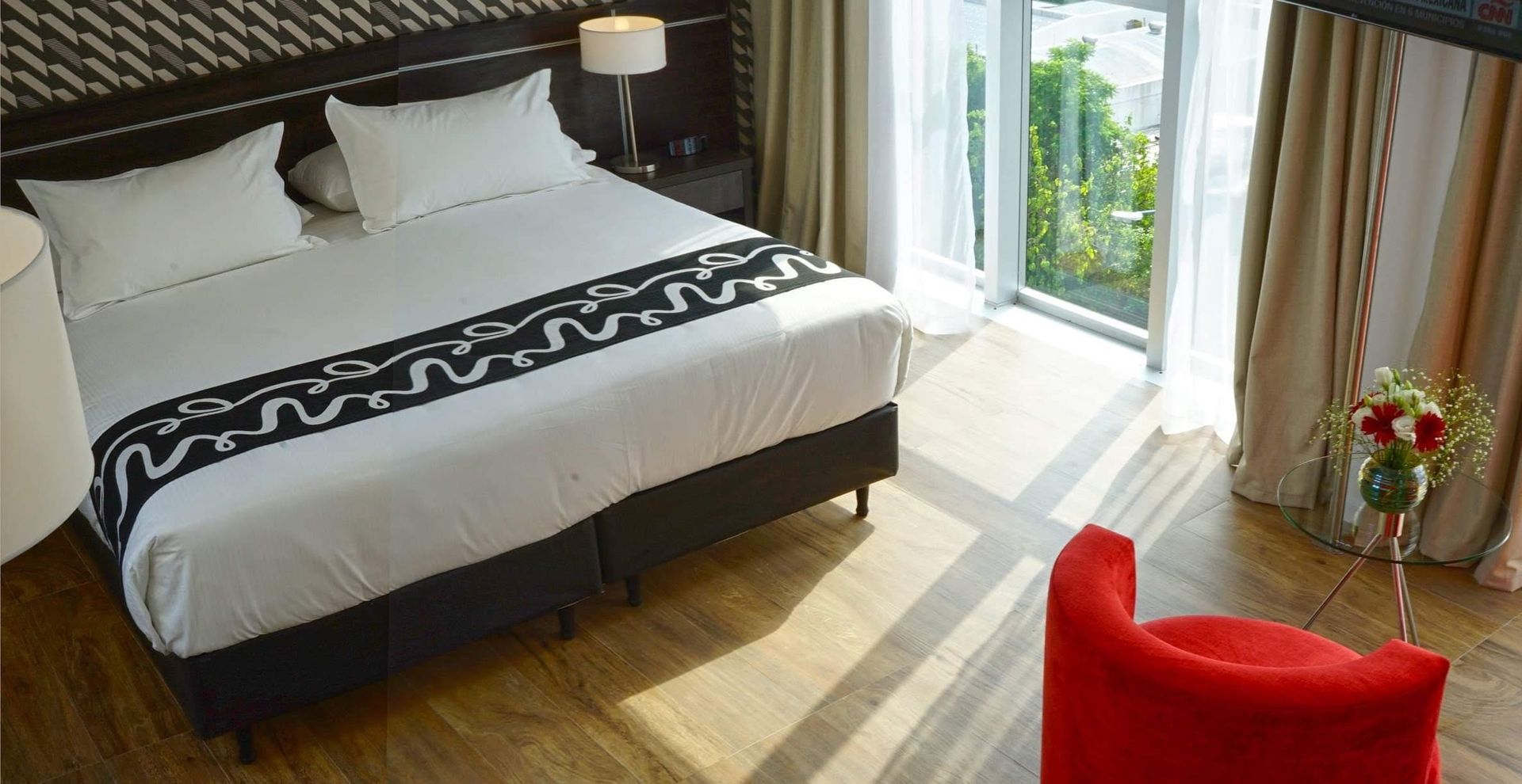 A hotel room with a large bed and a red chair