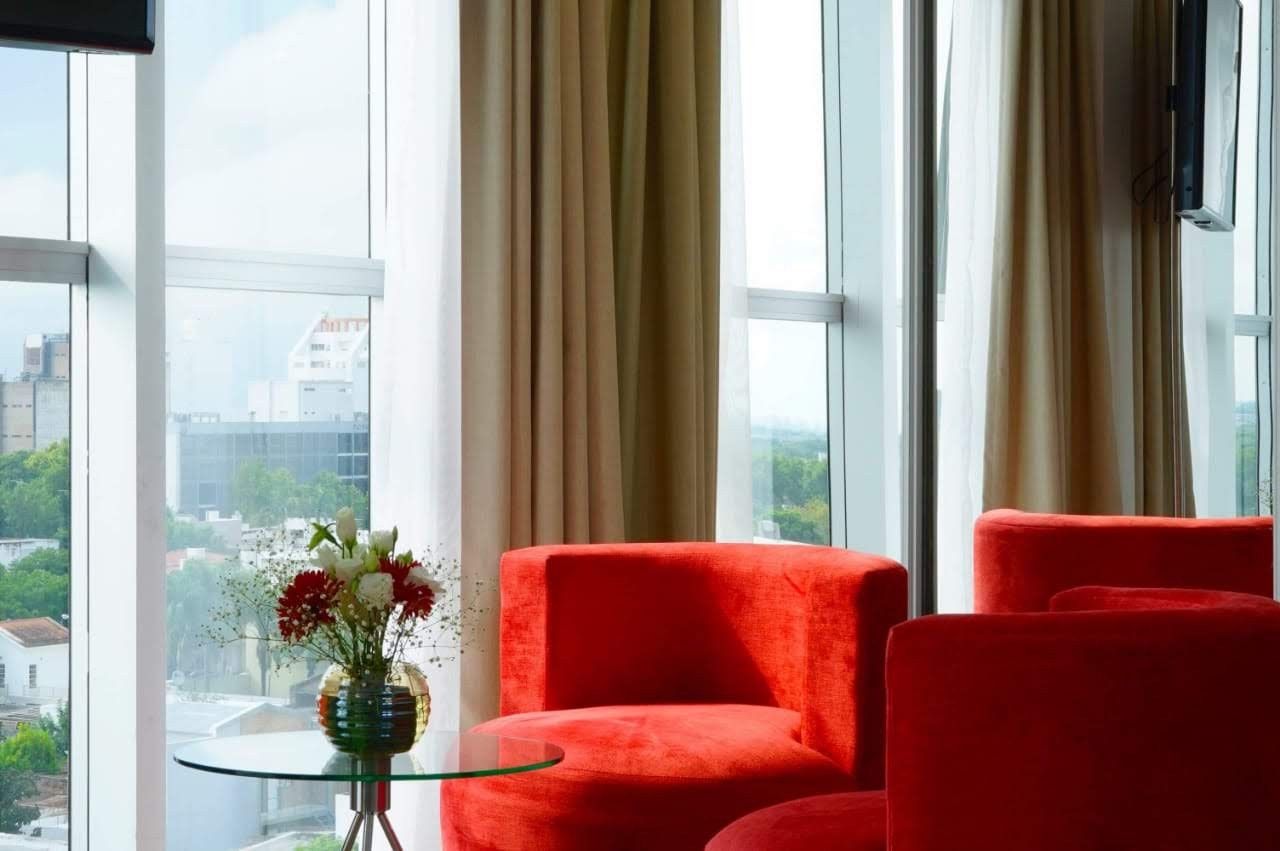 A living room with two red chairs and a table with a vase of flowers on it.