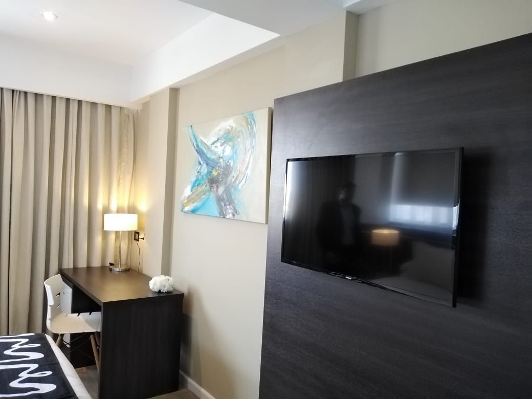 A hotel room with a desk and a flat screen tv