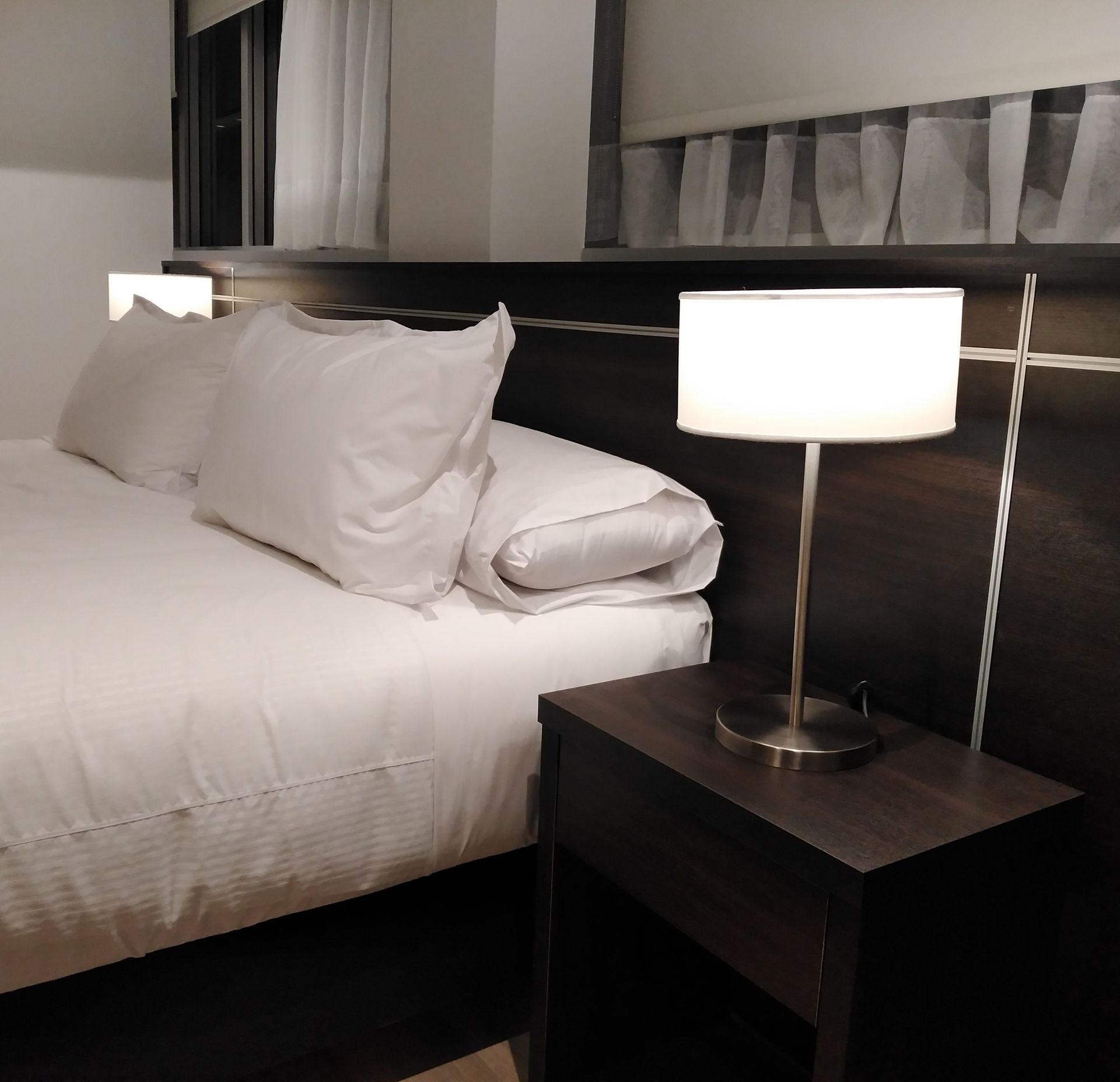 A bedroom with a bed and a lamp on a nightstand
