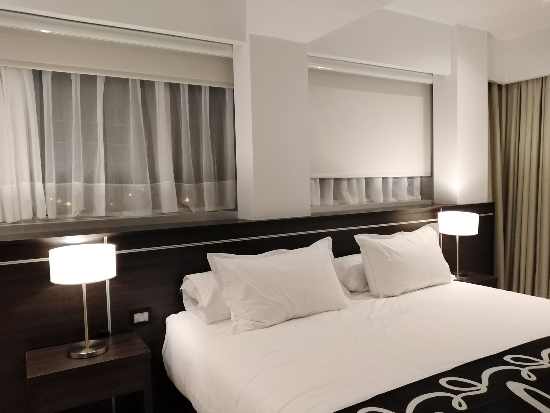 A hotel room with a king size bed and two lamps