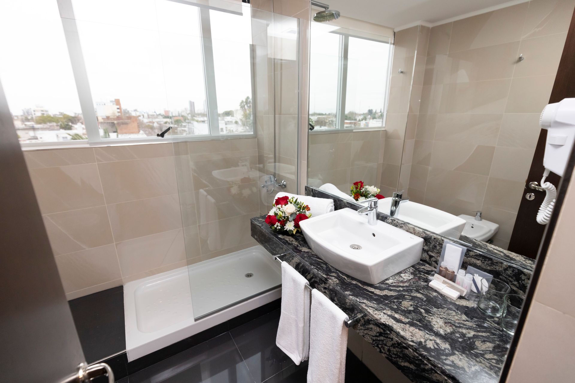 A bathroom with a sink , mirror , and shower stall.
