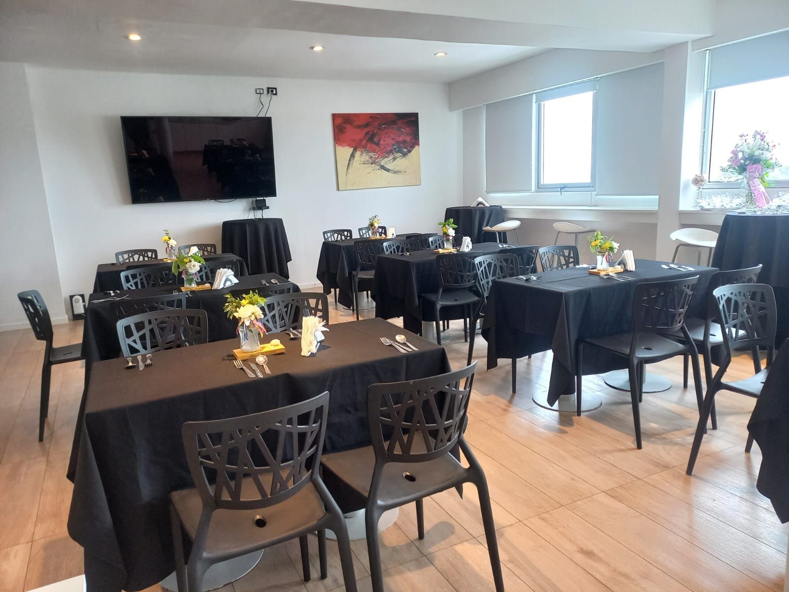 A large room with tables and chairs and a flat screen tv.