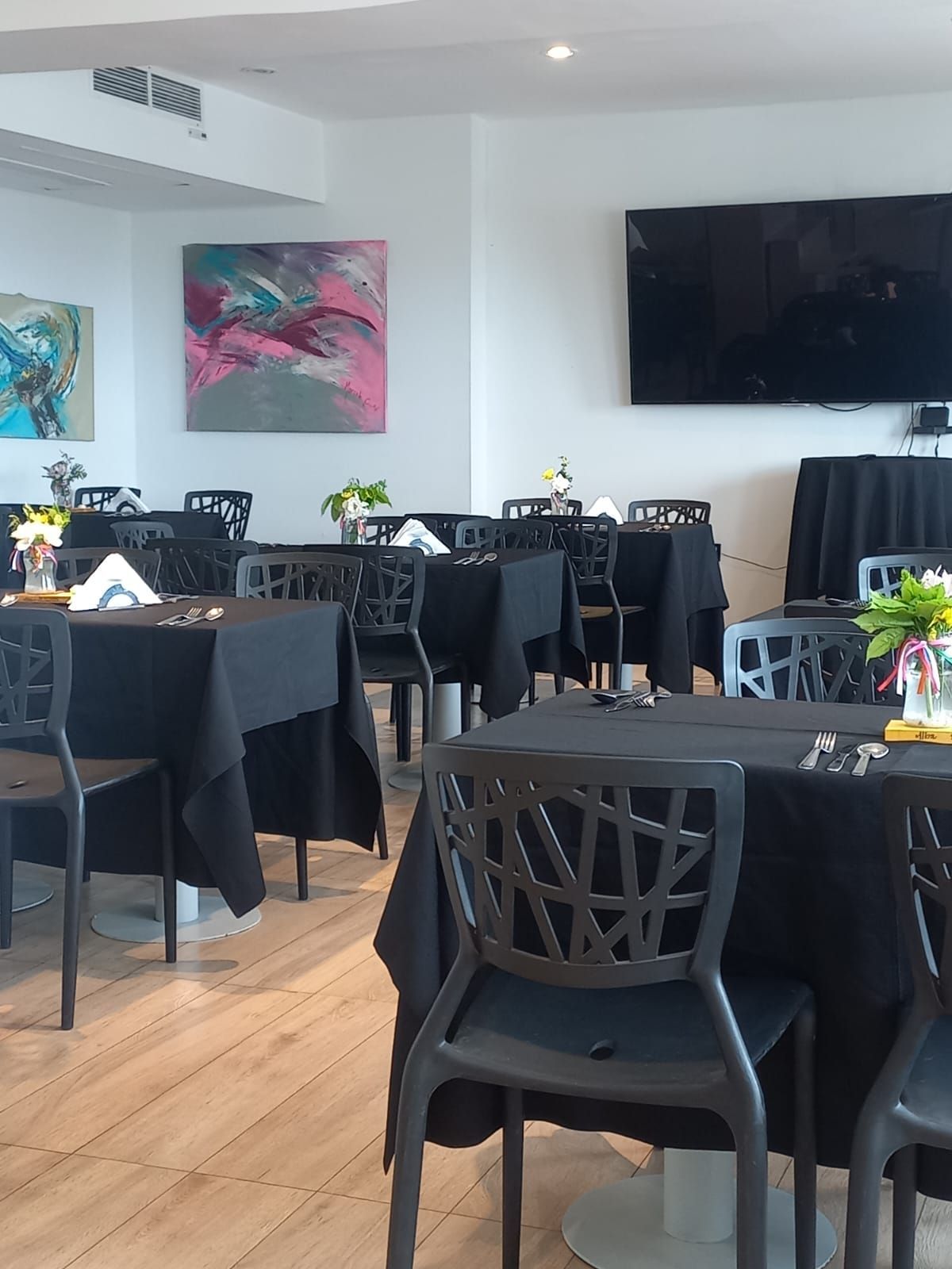 A dining room with tables and chairs and a flat screen tv