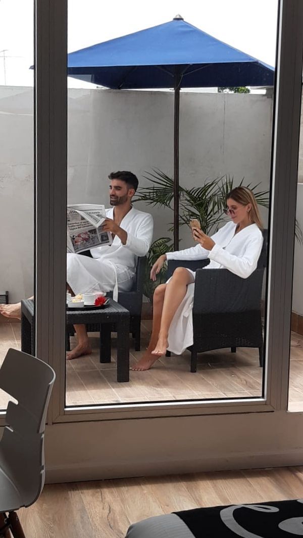 A man and a woman are sitting under an umbrella on a balcony.