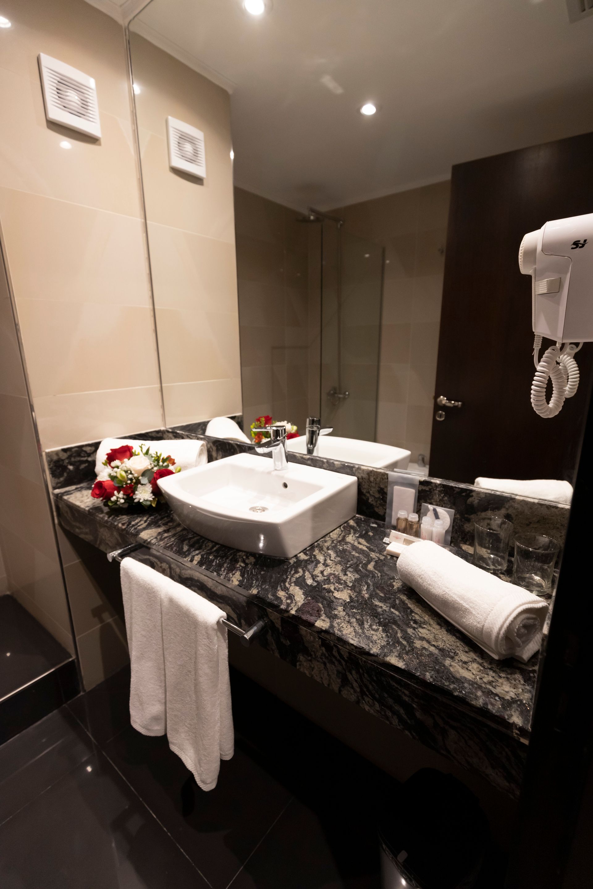 A bathroom with two sinks , a mirror and a hair dryer.