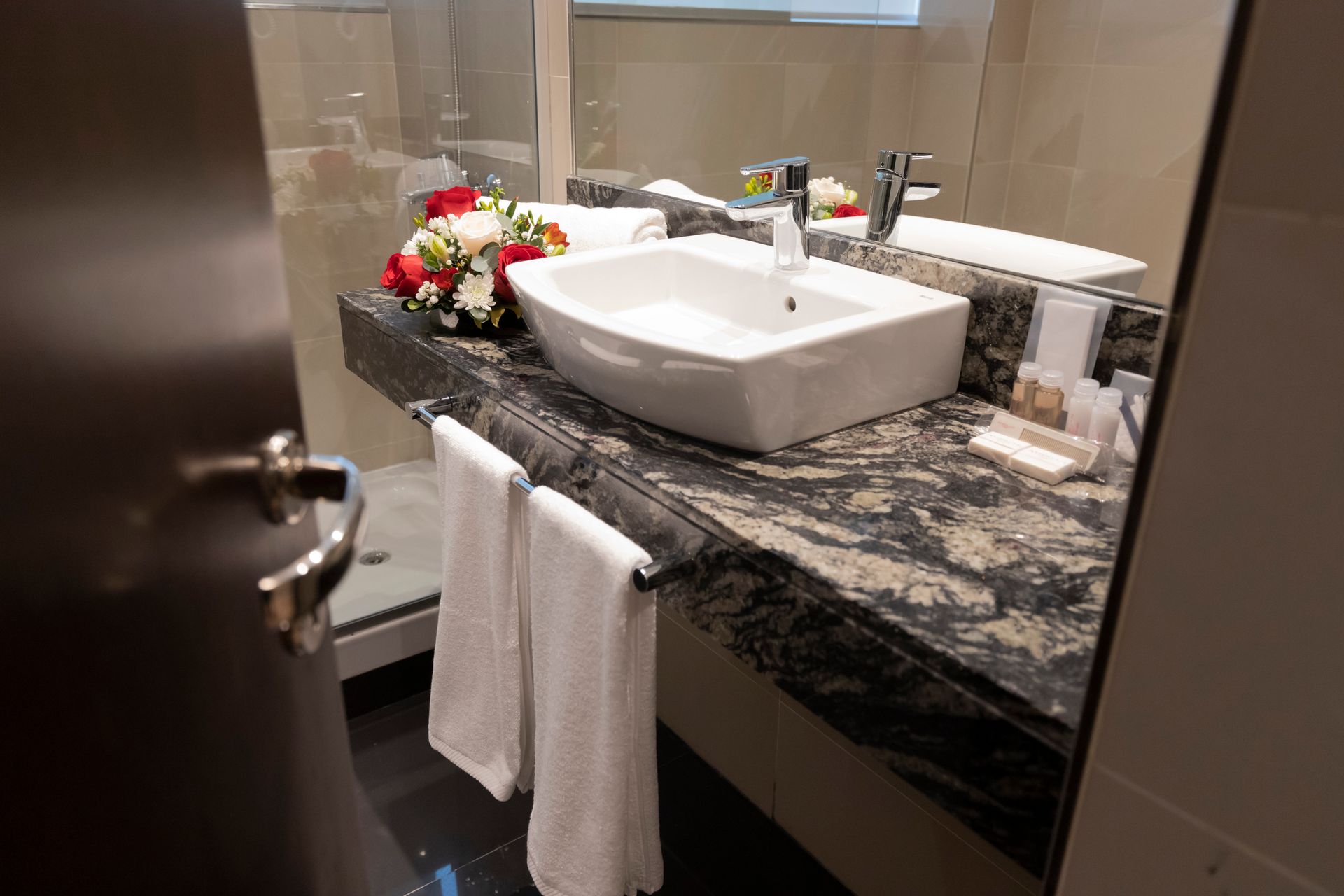 A bathroom with a sink , mirror , and towels.