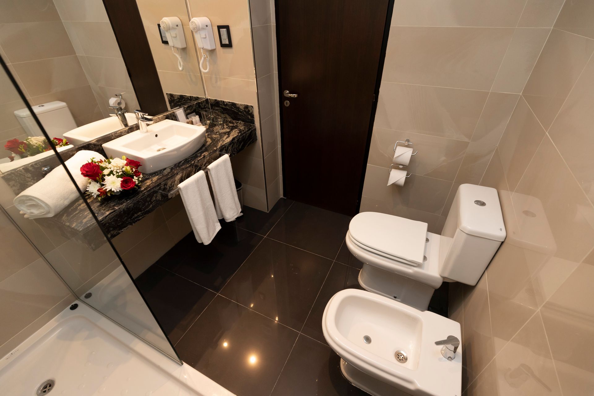 A bathroom with two toilets and a bidet