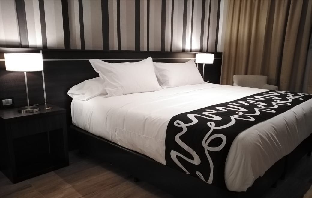 A hotel room with a large bed and a black and white blanket