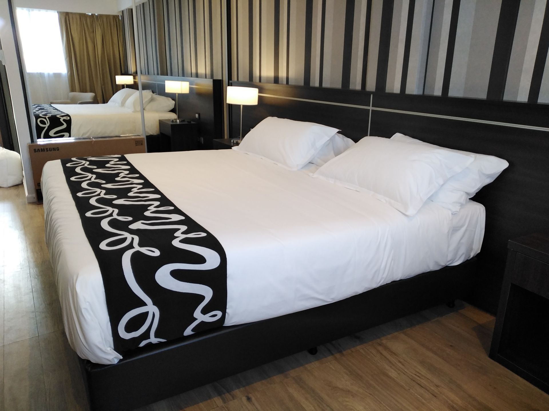A hotel room with a king size bed and striped walls