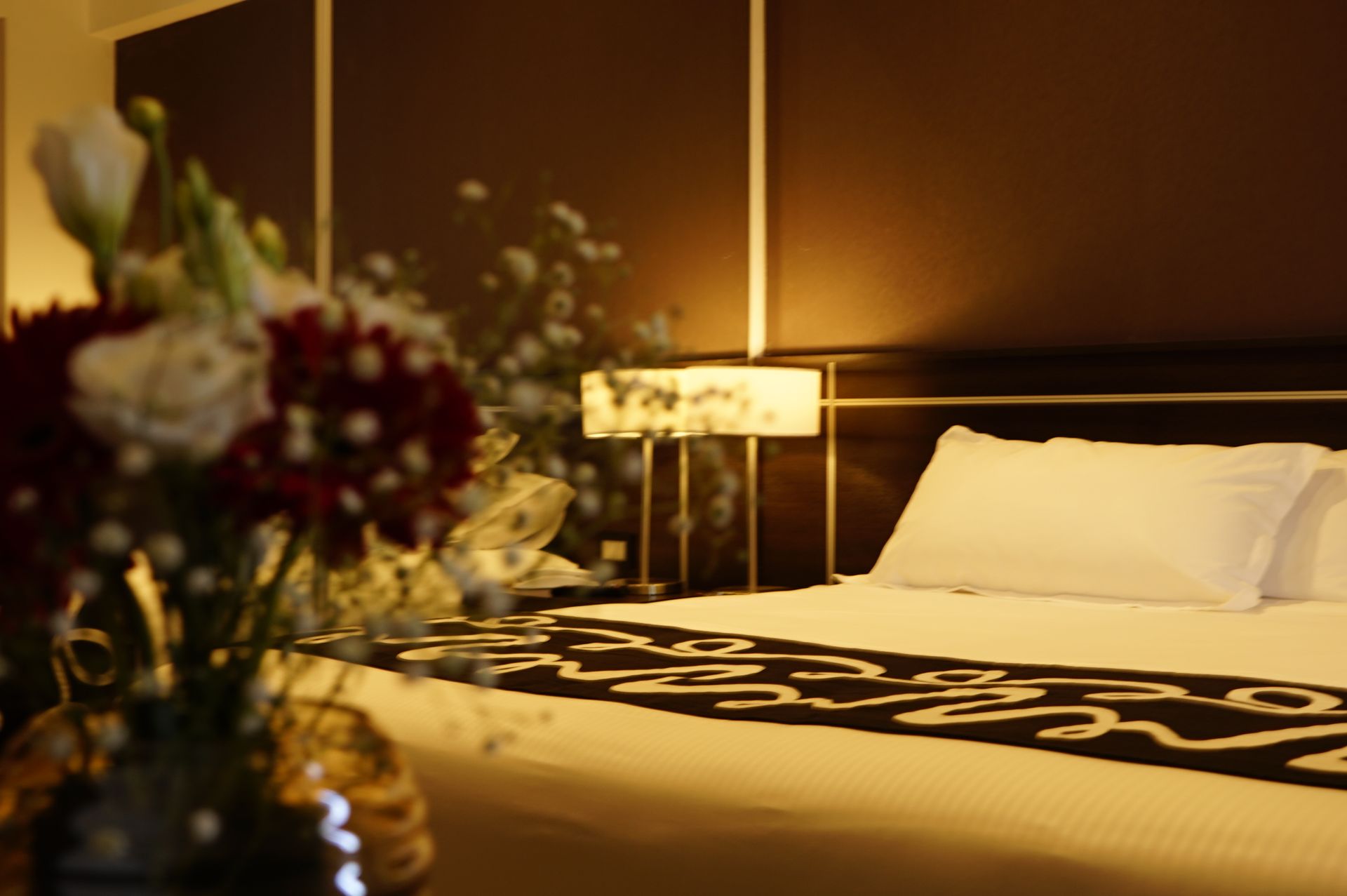 A hotel room with a bed and a vase of flowers