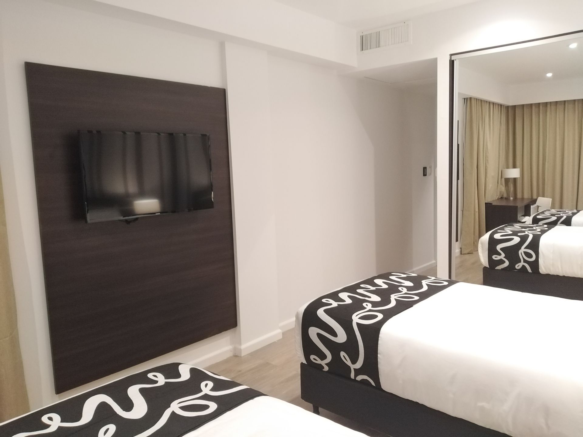 A hotel room with two beds and a flat screen tv on the wall.