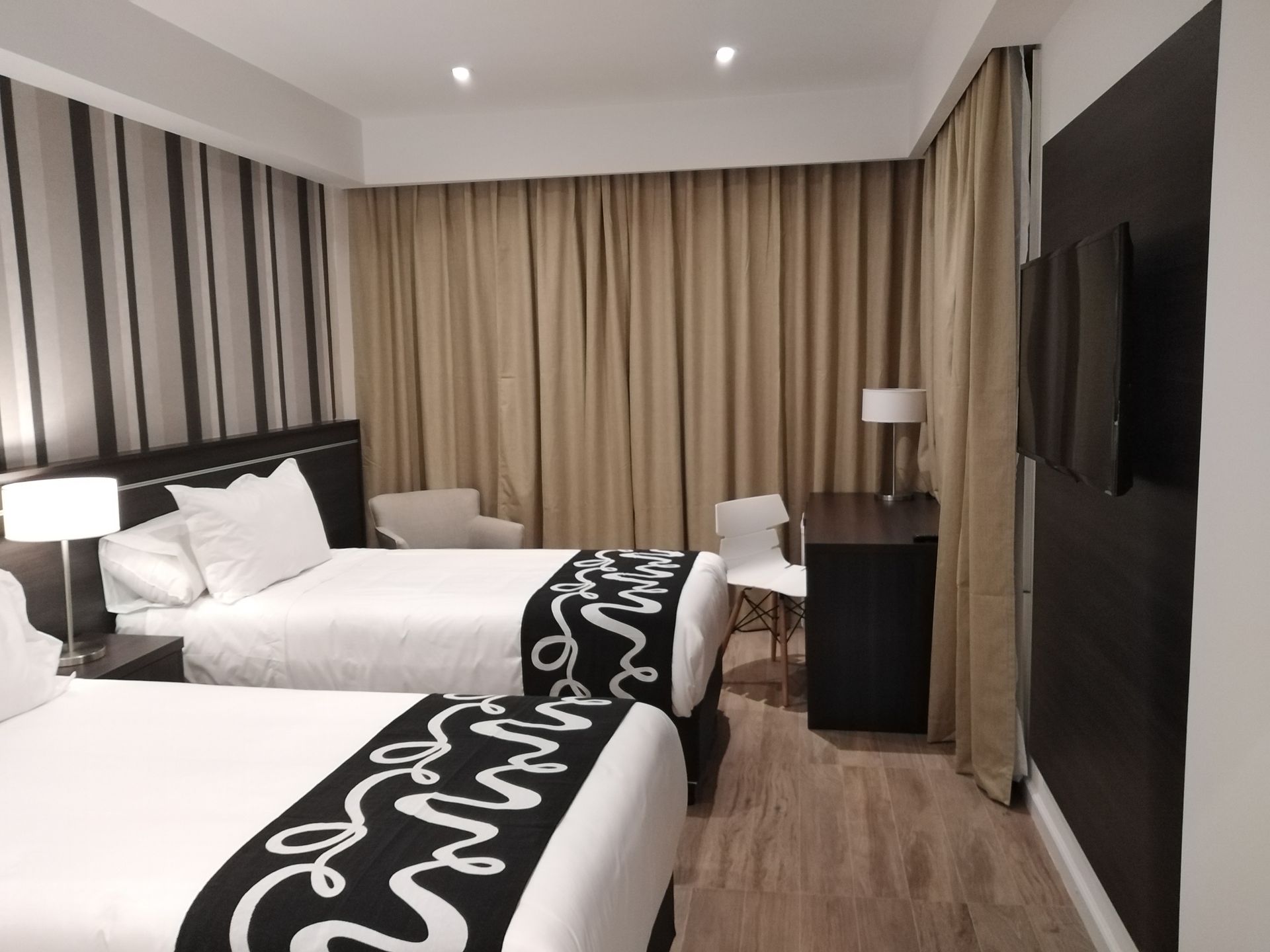 A hotel room with two beds , a desk and a television.