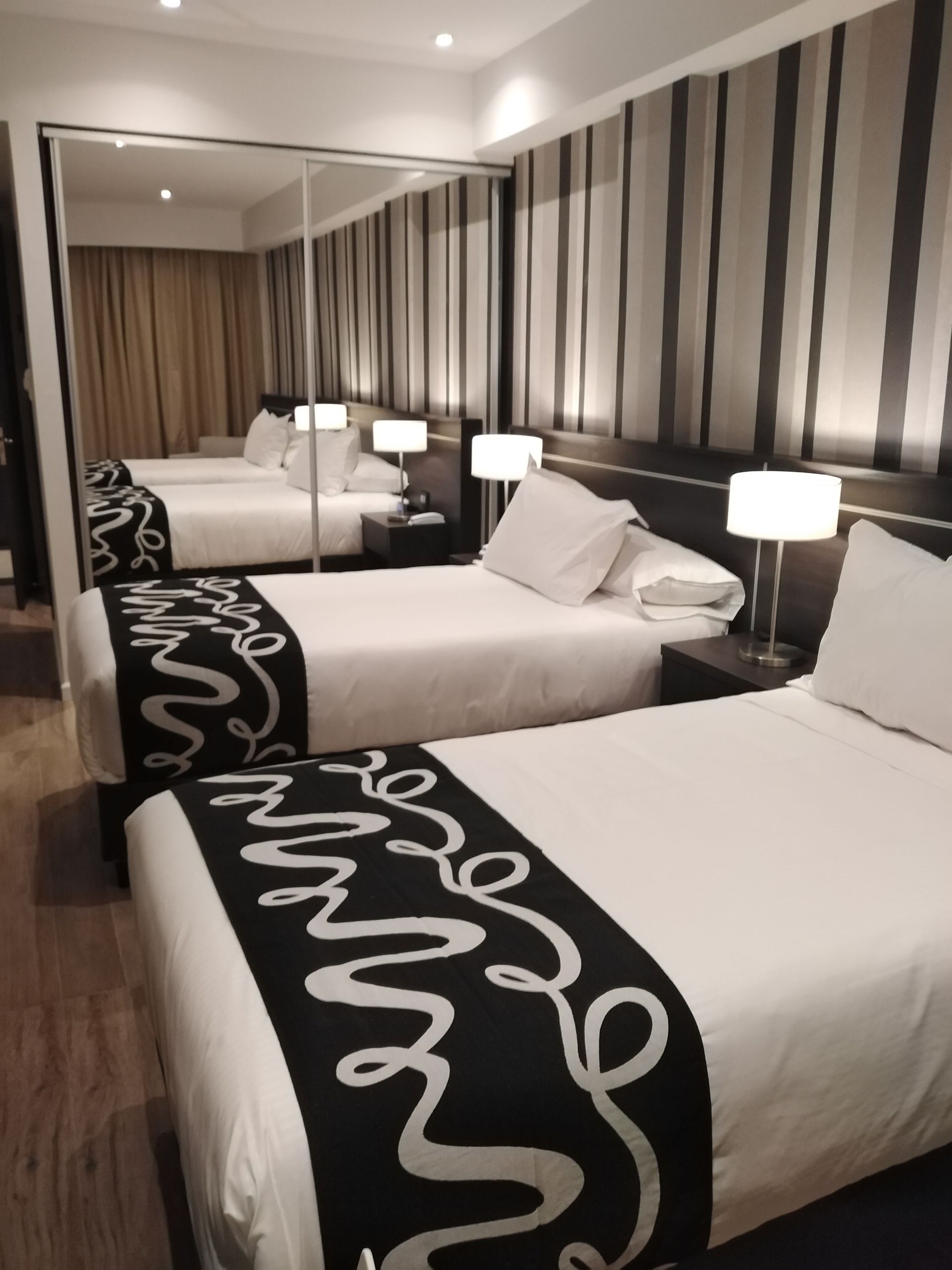 A hotel room with two beds and a mirror