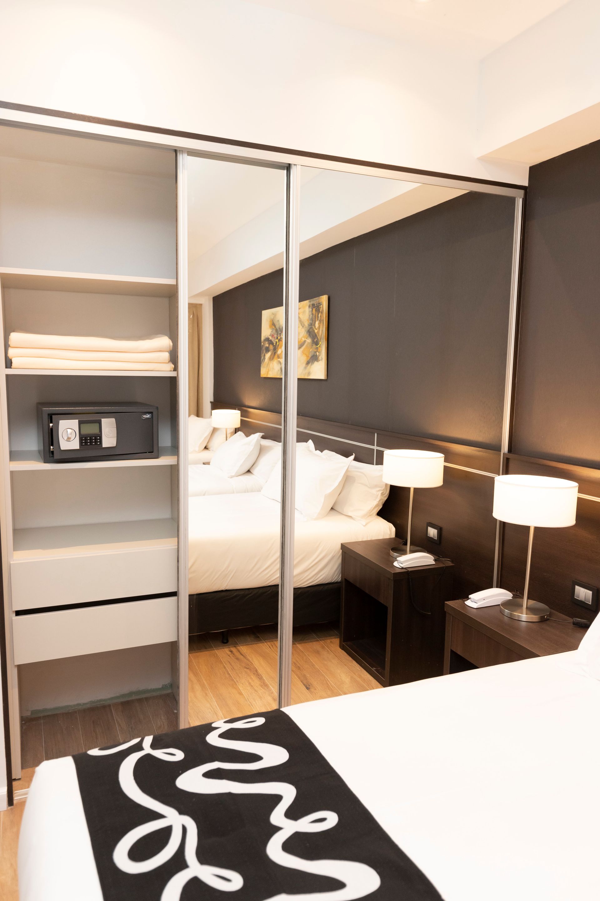 A hotel room with a bed , nightstand , lamps and a sliding glass door.