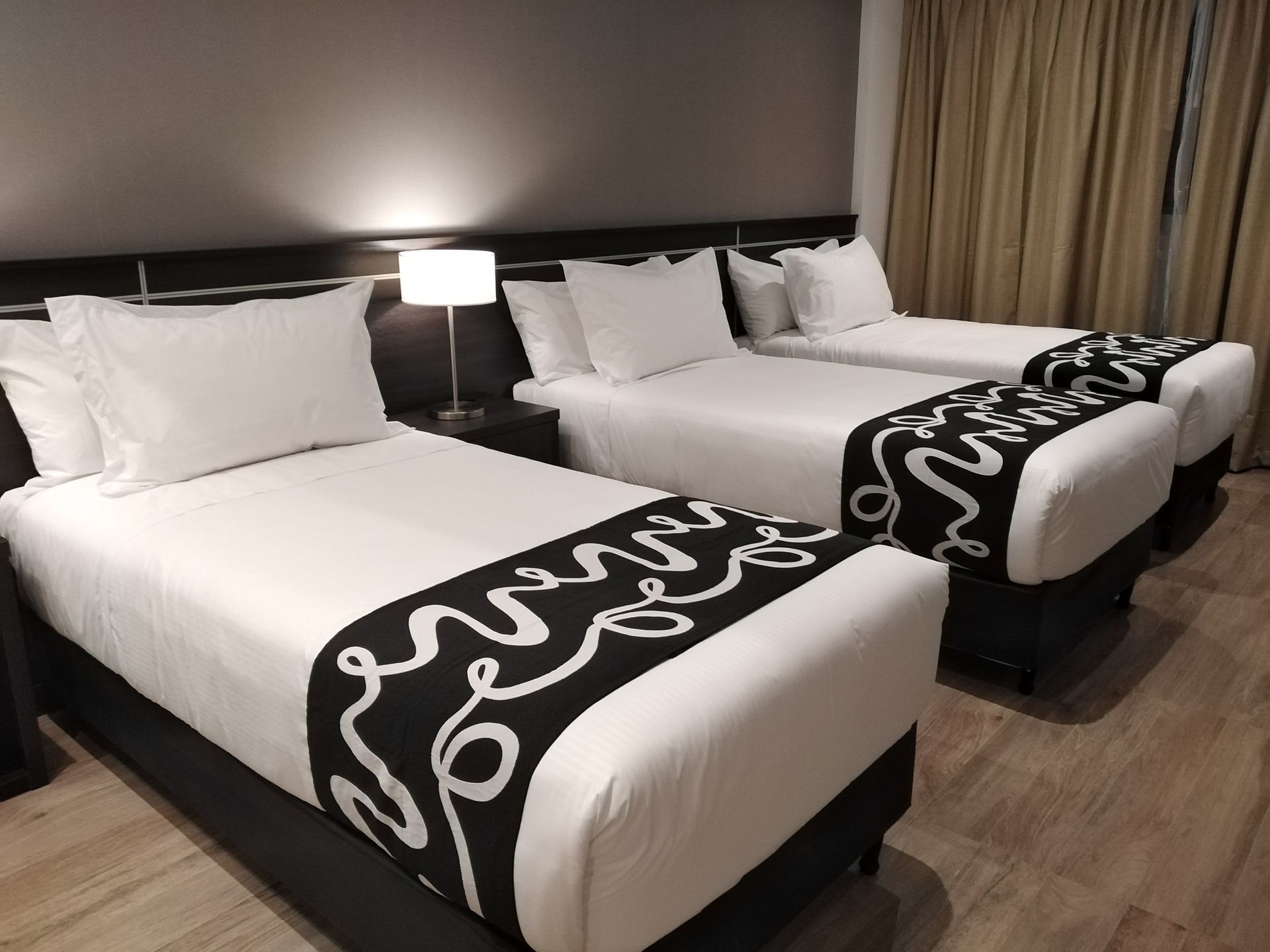 A hotel room with three beds and a lamp