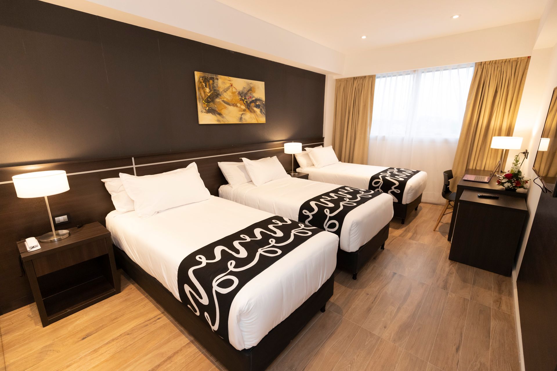 A hotel room with three beds and a painting on the wall.
