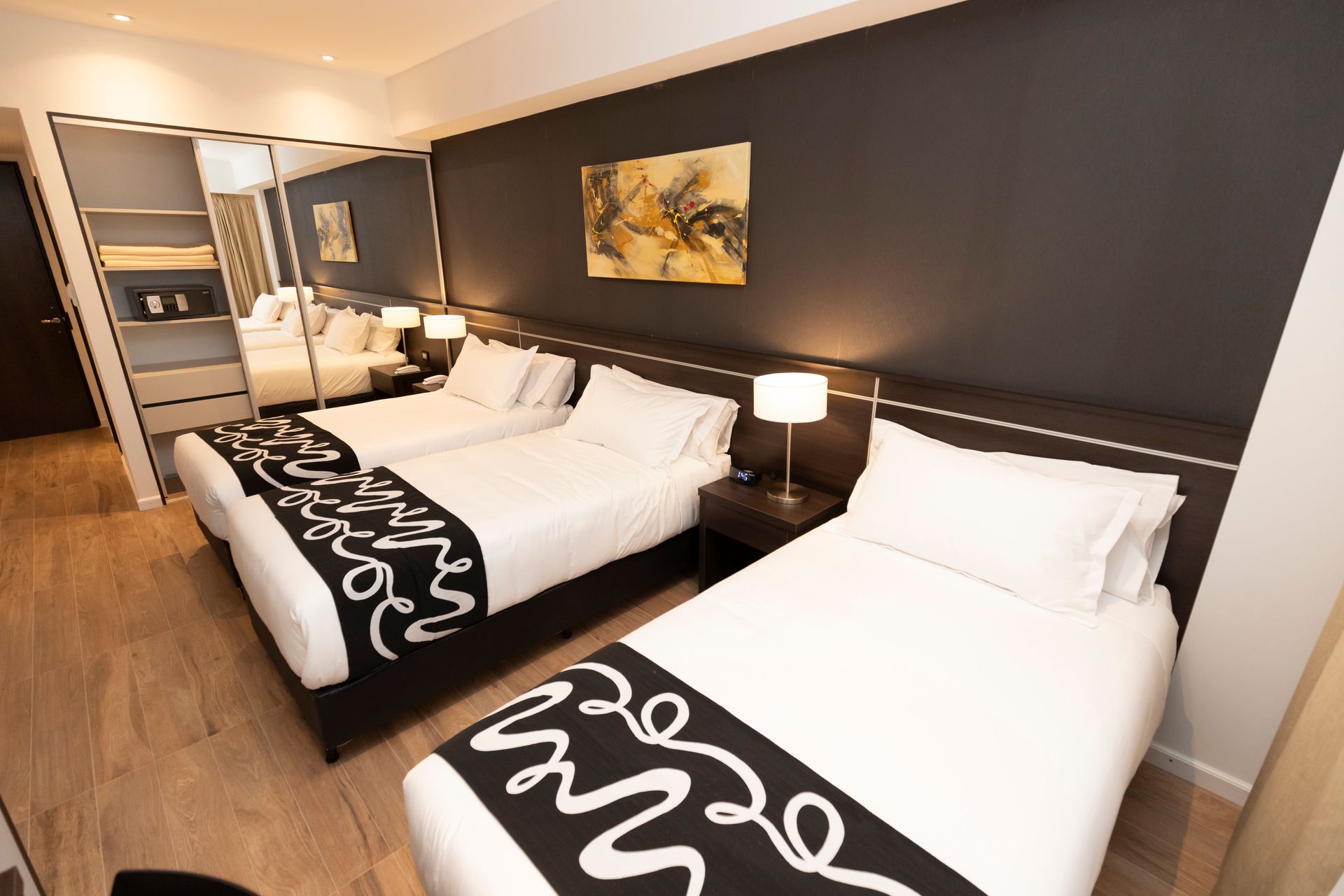 A hotel room with three beds and a painting on the wall.