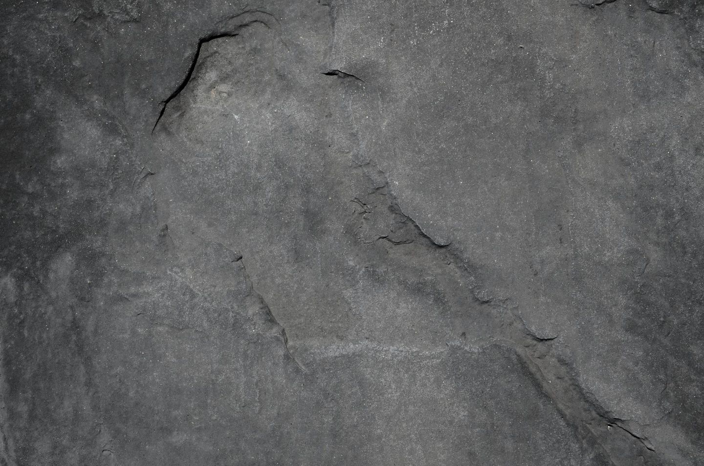 Gray textured stone surface with cracks and varying tones.