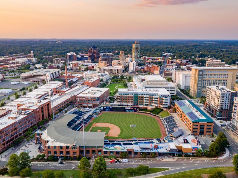 An aerial view of a city with a baseball field in the middle of it.