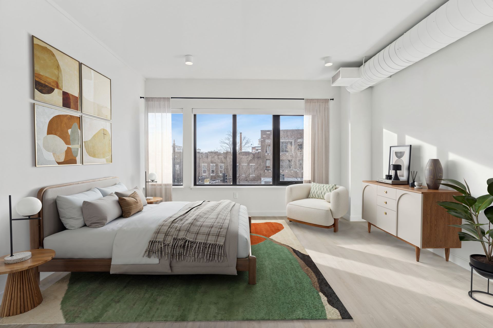 A bedroom with a bed , chair , dresser and rug.