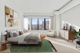 A bedroom with a bed , chair , dresser and rug.