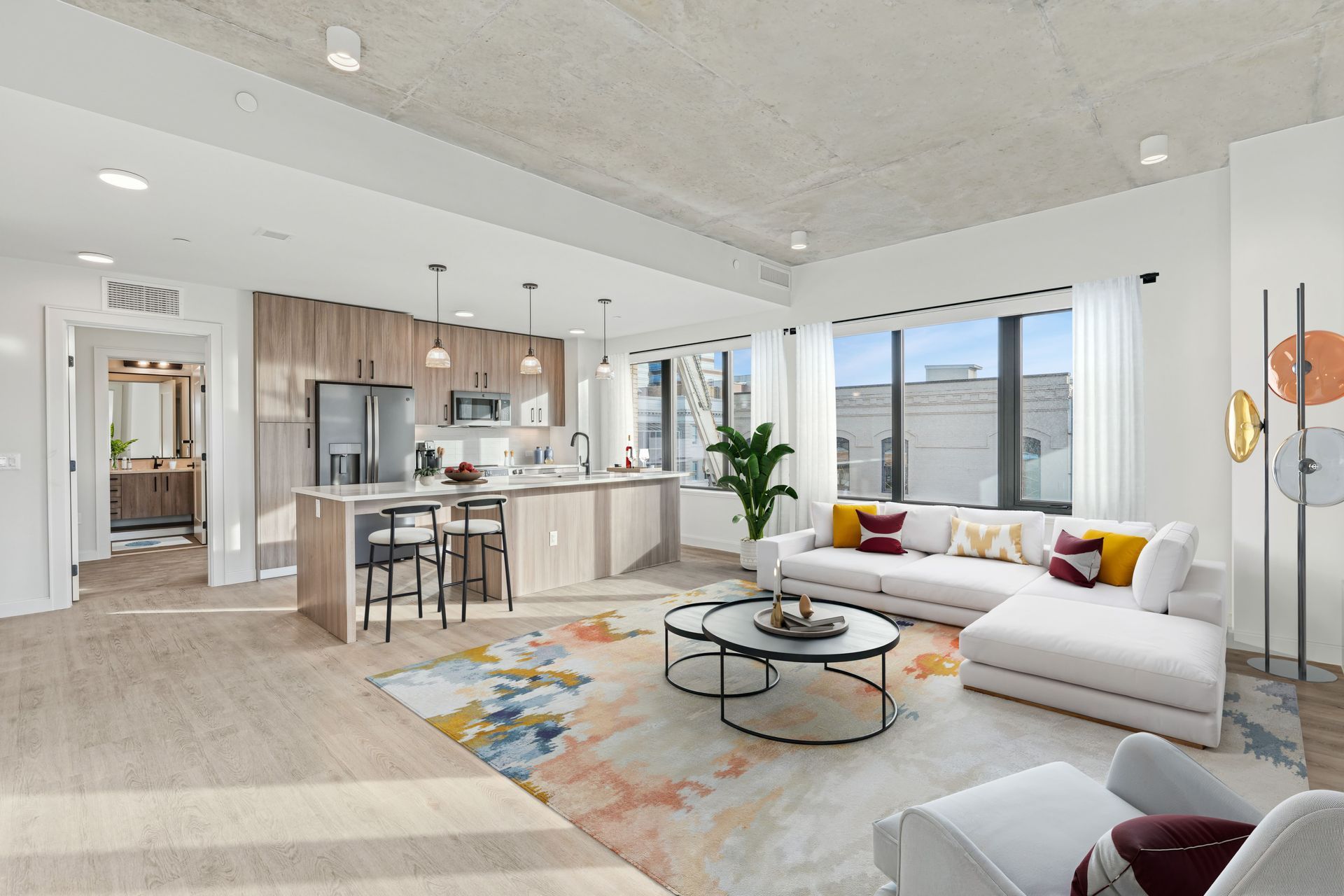 A living room with a couch , chair , coffee table and kitchen.
