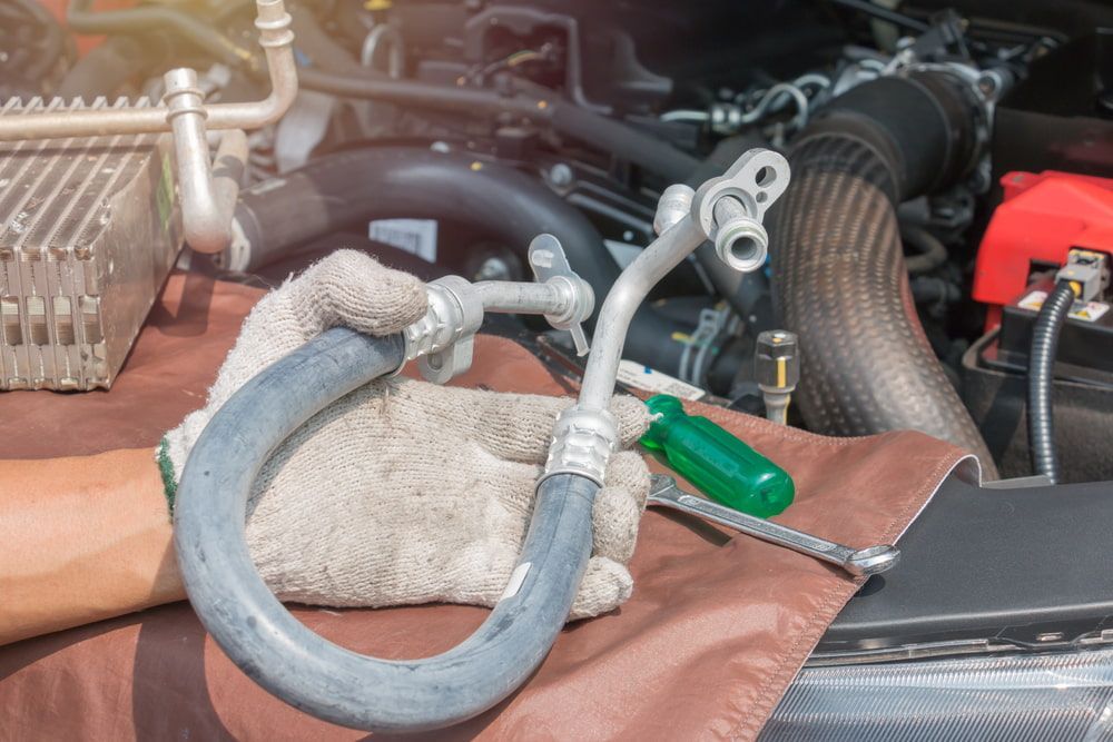 A Person Is Working on A Car with A Hose and A Screwdriver — Wyong Radiator Repairs in Gosford, NSW