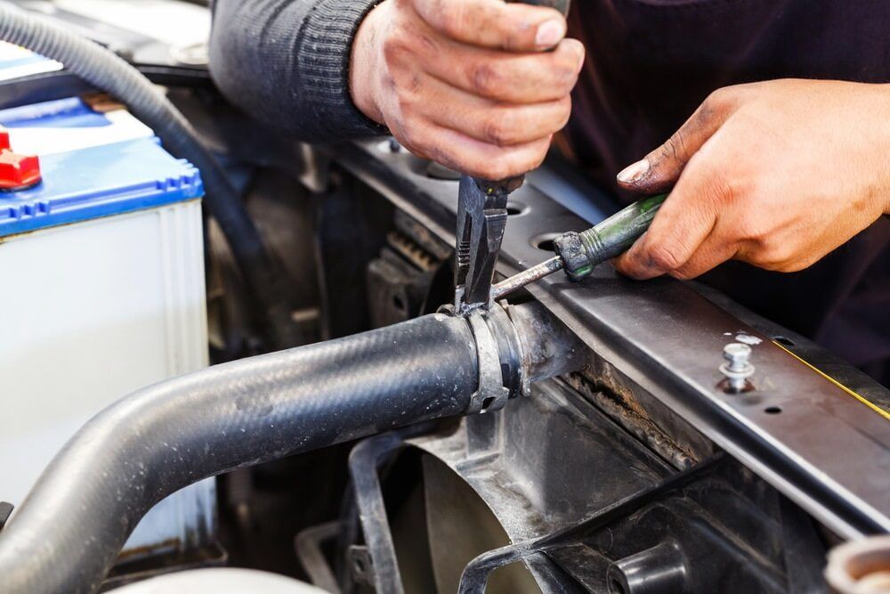 A Man is Working on a Car Radiator With a Screwdriver — Wyong Radiator Repairs In Budgewoi, NSW