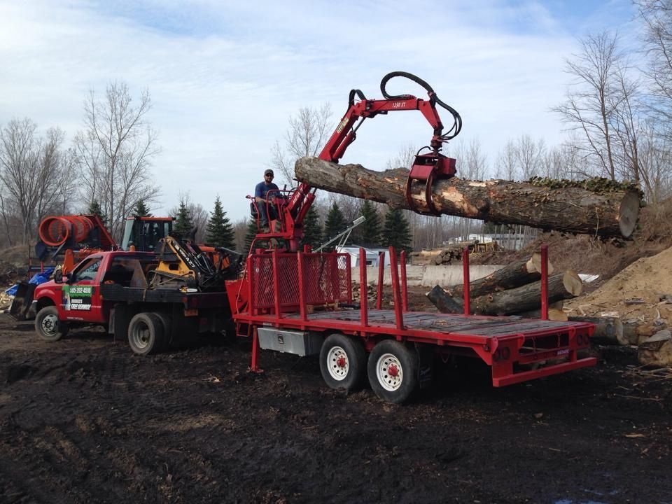 A red truck is carrying a large log on a trailer.