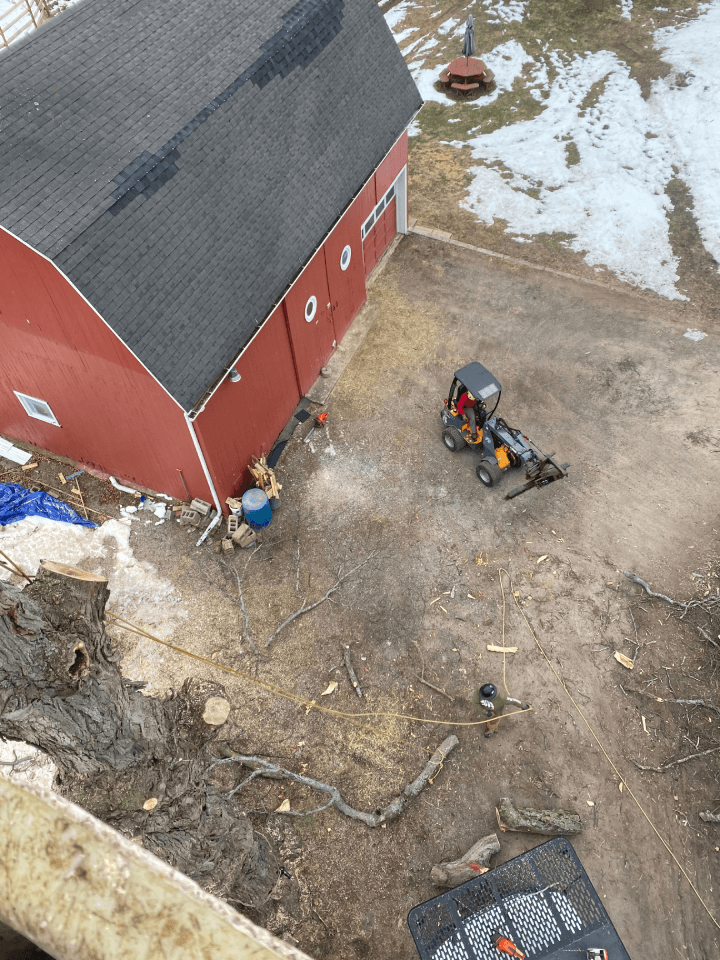 An aerial view of a red barn with a tractor parked in front of it.