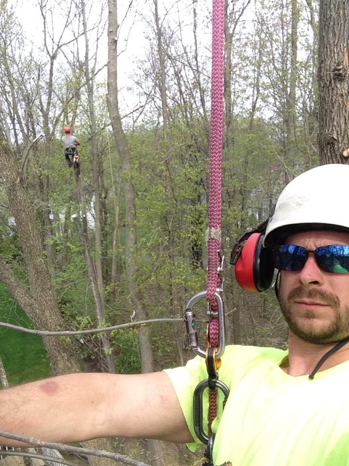A man wearing a helmet and sunglasses is standing next to a tree.