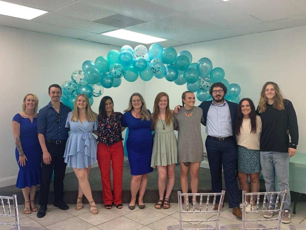 A group of people are posing for a picture in front of balloons at KCMI.