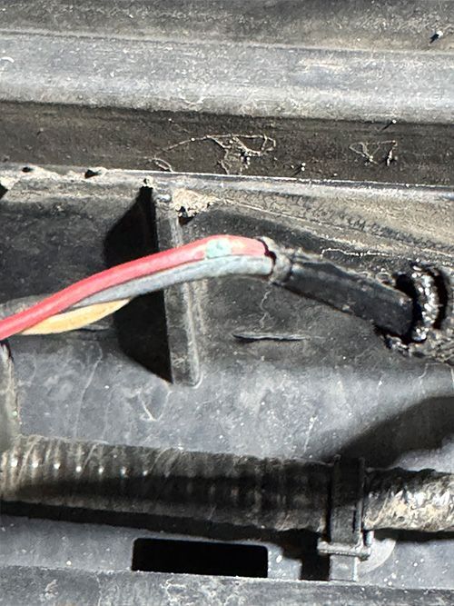 Close-up of cut wires with exposed colored conductors; red, gray, and yellow wires visible. Black electrical tape around the cut  | S&C Automotive Inc