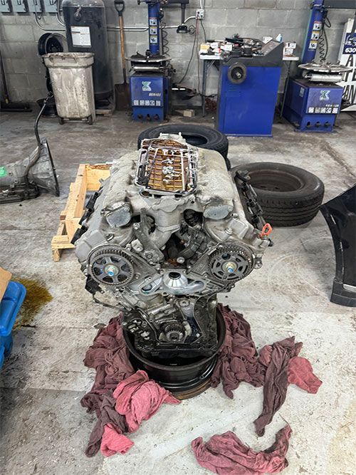 Engine on a pallet in a garage, surrounded by tools and equipment  | S&C Automotive Inc