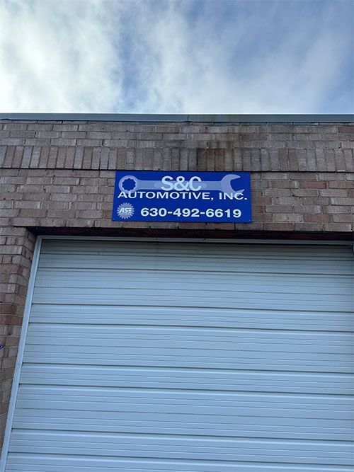 S&C Automotive, Inc. sign on a brick building above a closed garage door; phone number   | S&C Automotive Inc
