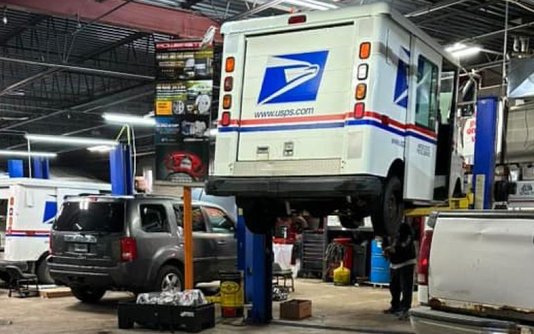 A USPS mail truck on a lift inside a mechanic's garage, other vehicles present | S&C Automotive Inc