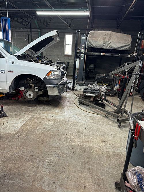 White truck with open hood in auto repair shop, engine on cart nearby  | S&C Automotive Inc