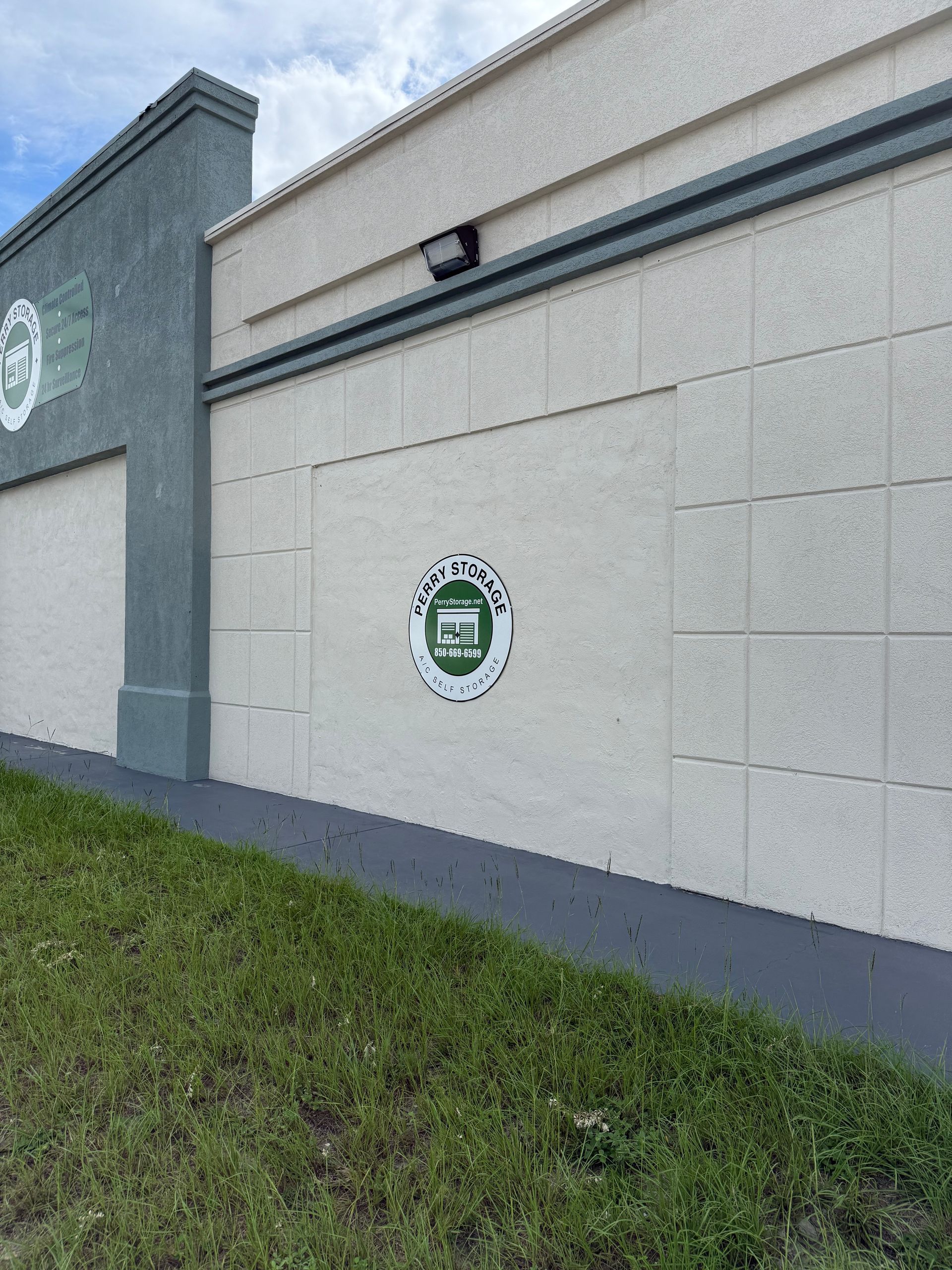 Exterior wall with a green and white logo; grey and white building.