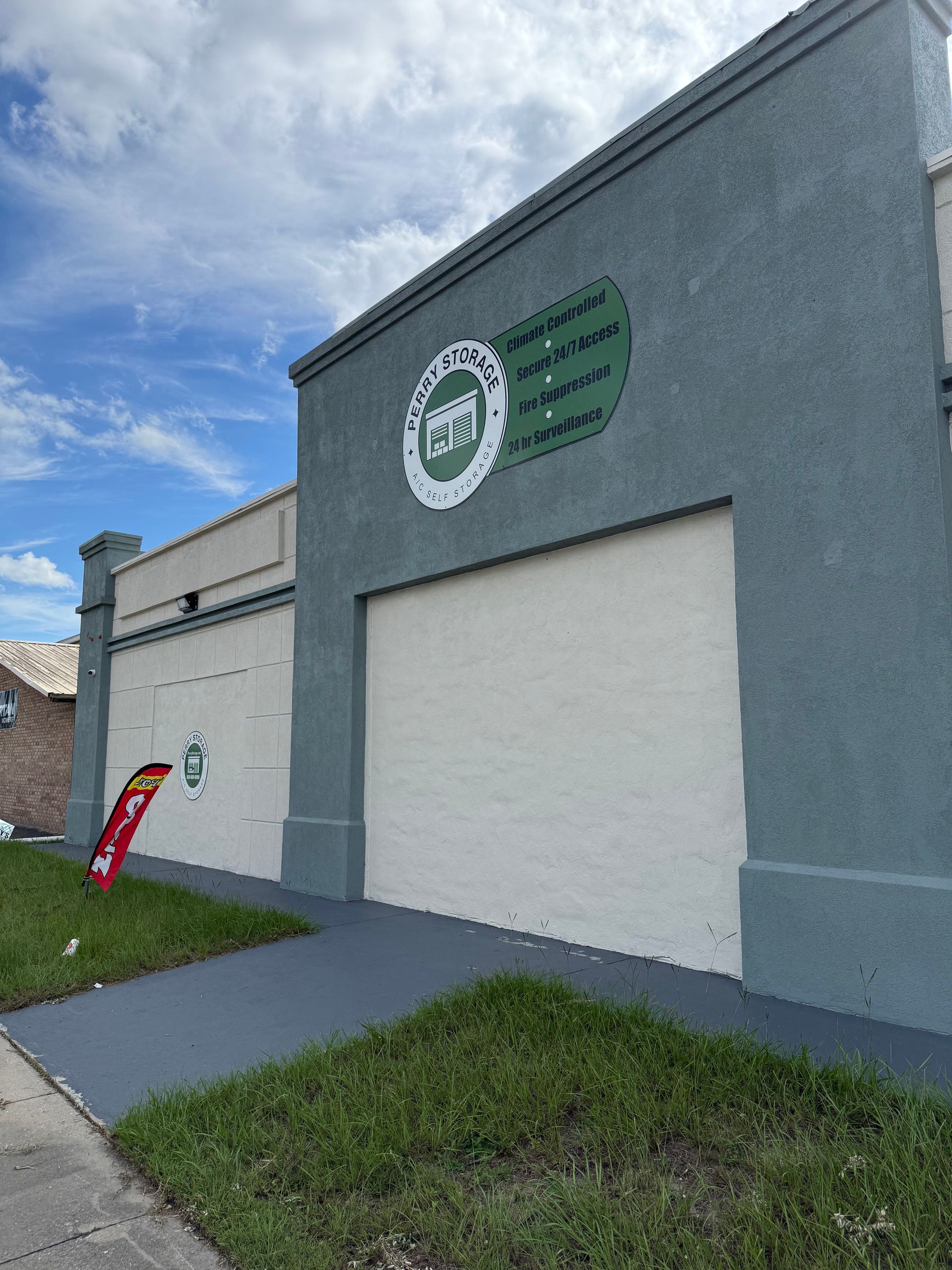 Exterior of ATI building with blue/green facade, gray ramp, and a green lawn.
