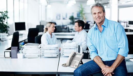 Man sitting at desk with NEC Phone next to him