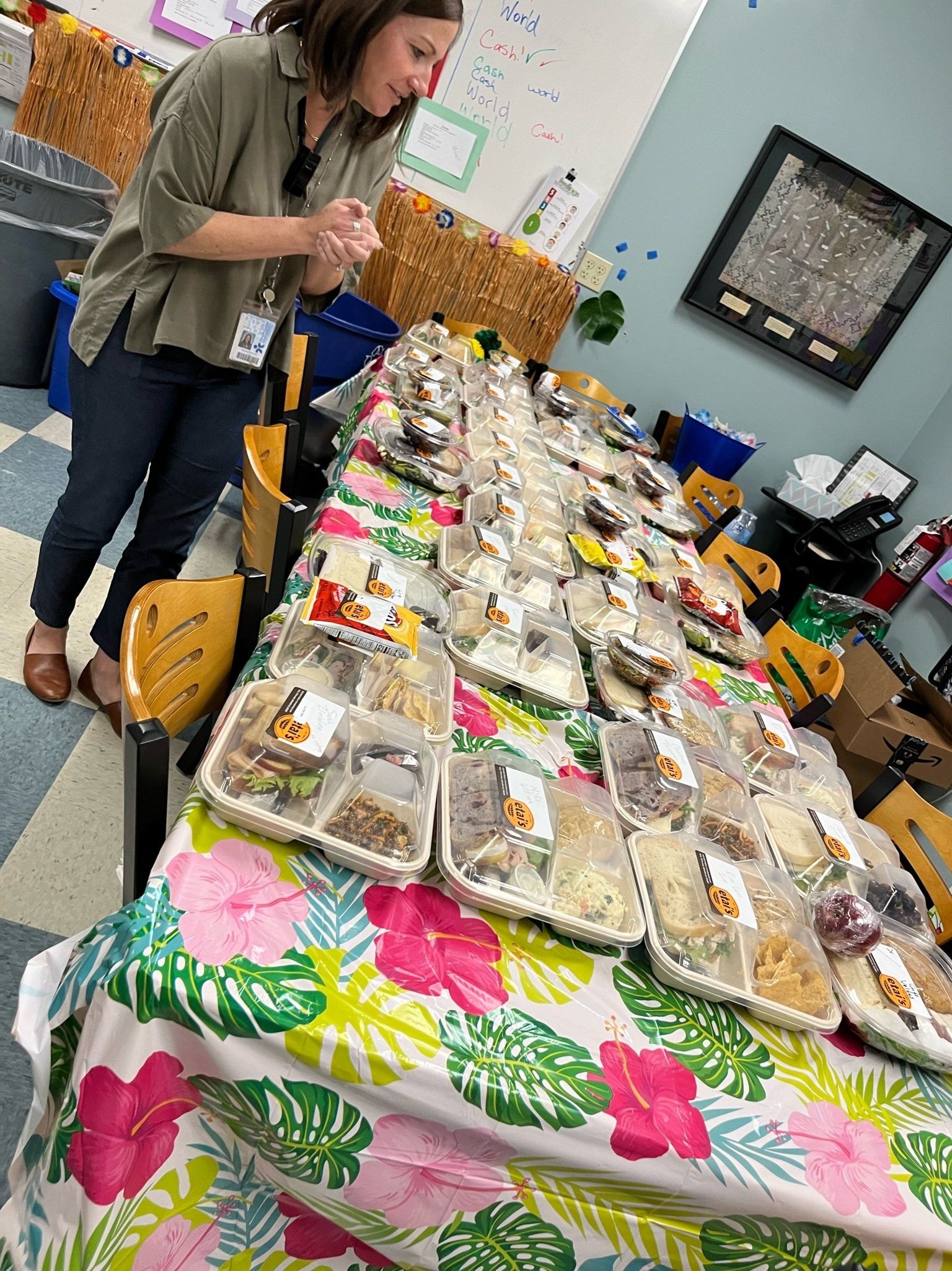 A woman is standing next to a long table filled with lots of food.