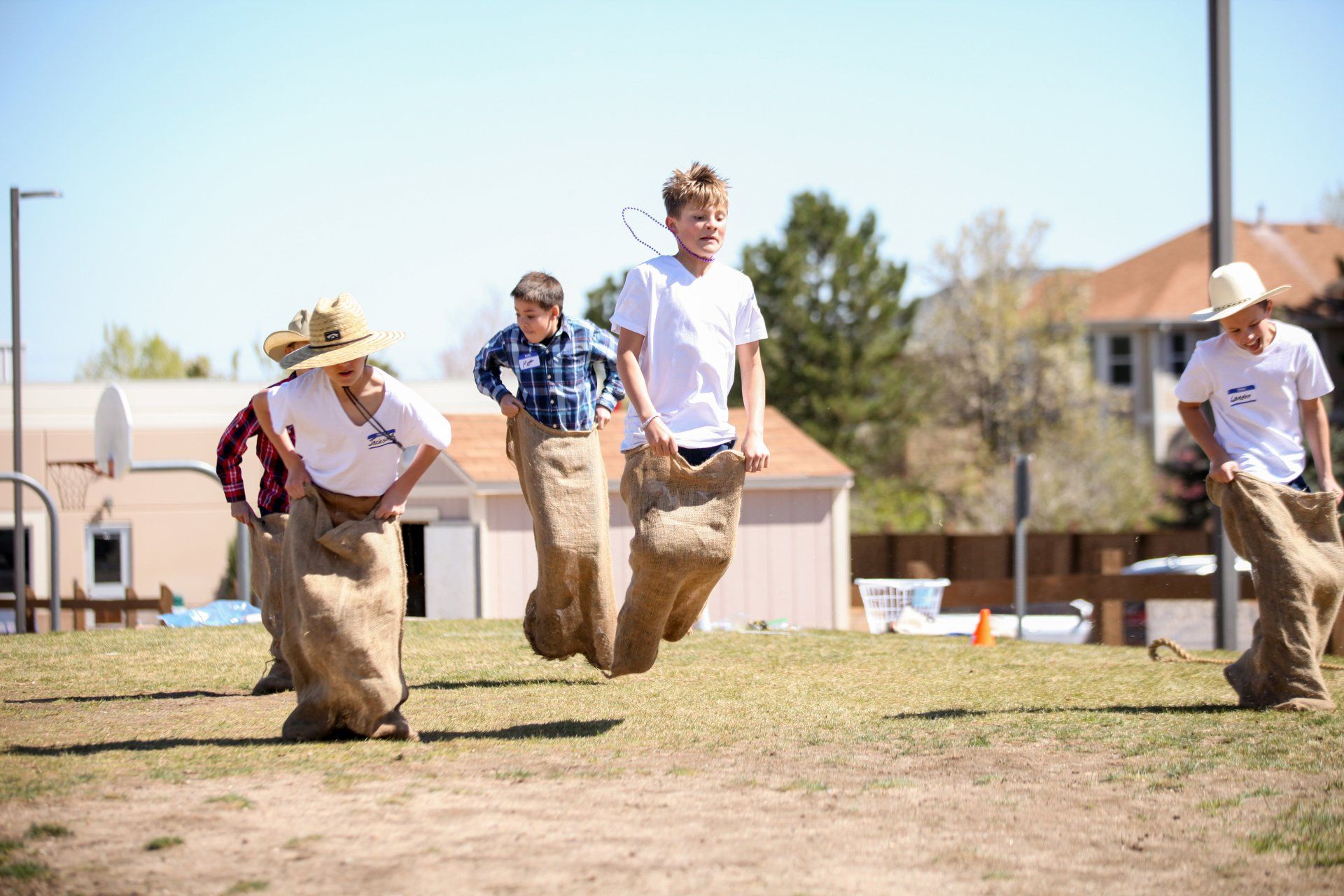 A group of young men are jumping in sacks in a field.