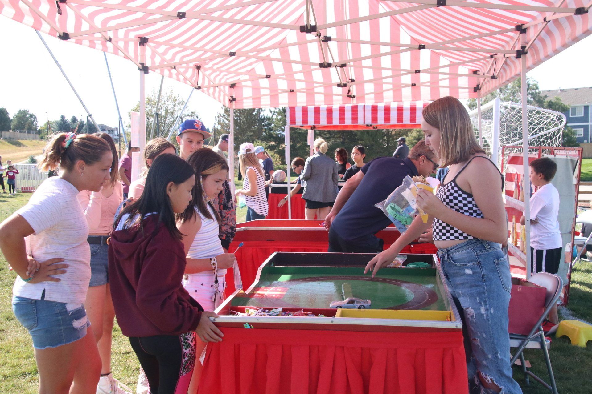 A group of people are standing around a table at a carnival.