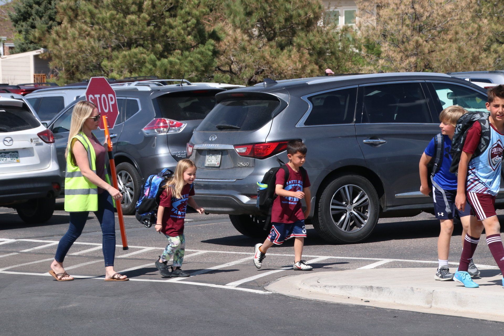 A group of children are crossing the street in front of a stop sign.