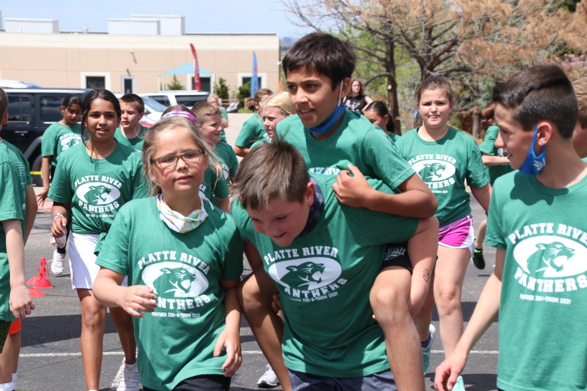 A boy is carrying a girl on his shoulders in a parade.