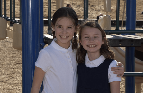 Two young girls are posing for a picture at a playground