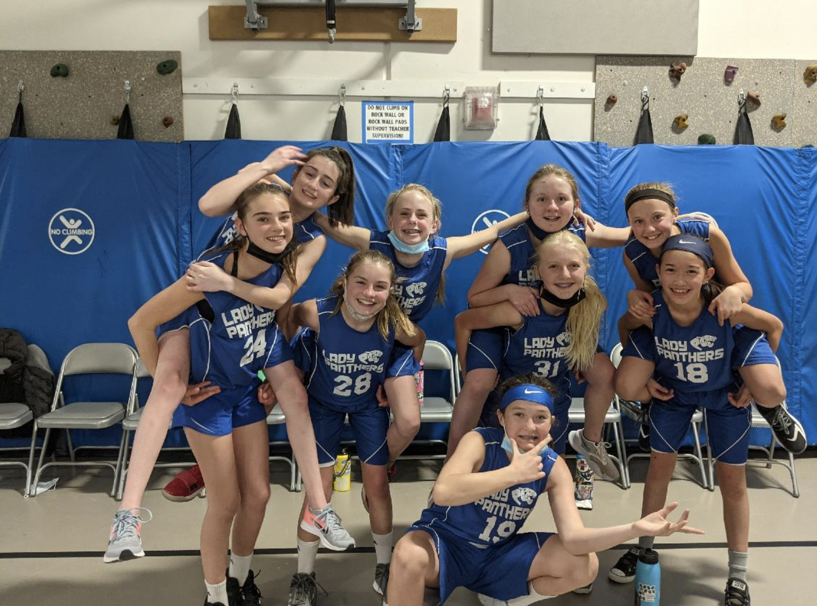 A group of young girls are posing for a picture in a gym.
