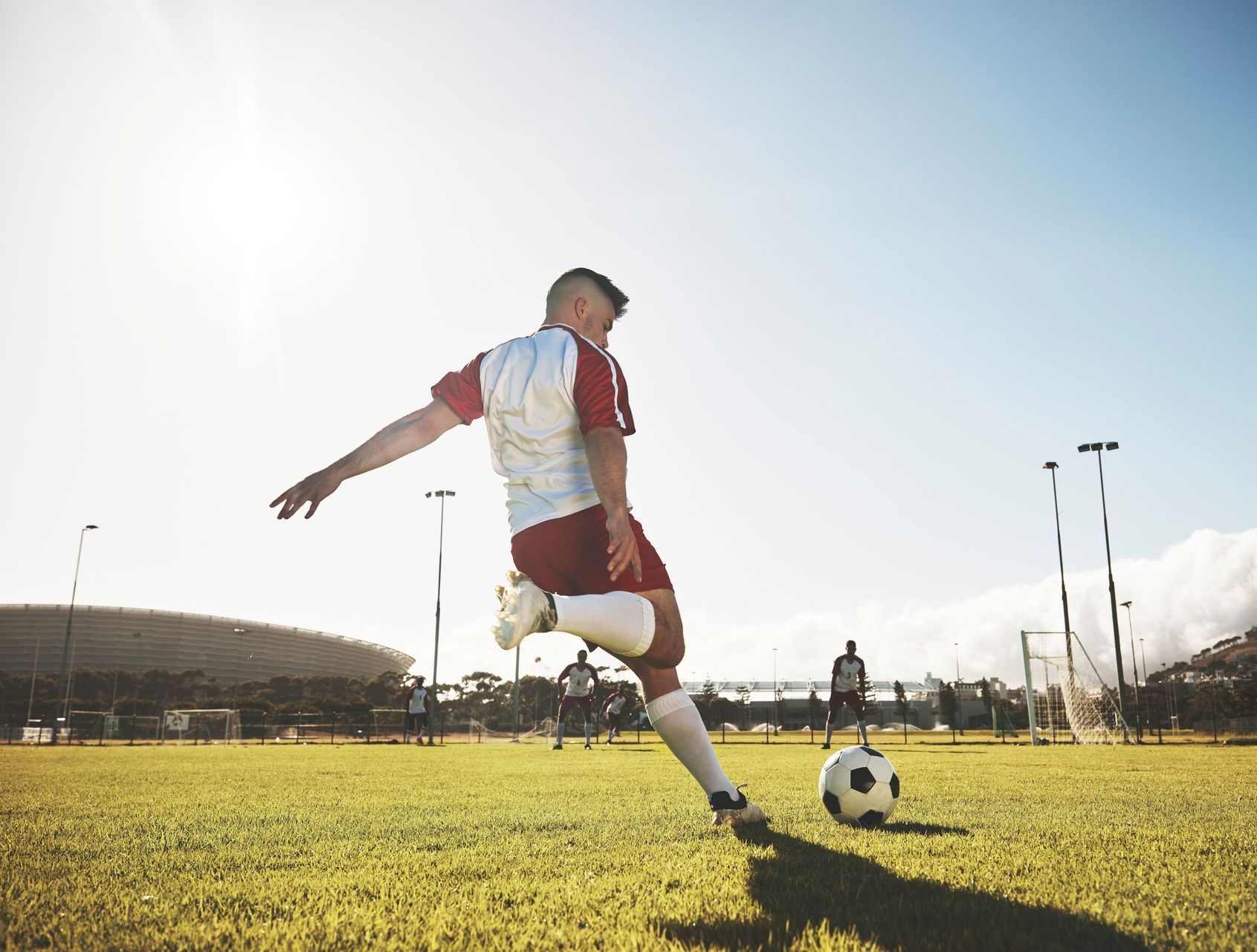 teenage boy playing soccer in a sunny field